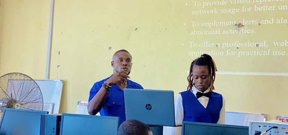 Two students presenting a network monitoring web application in the college's computer lab