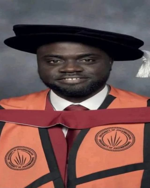 Man in a black doctoral cap and an orange and maroon academic gown